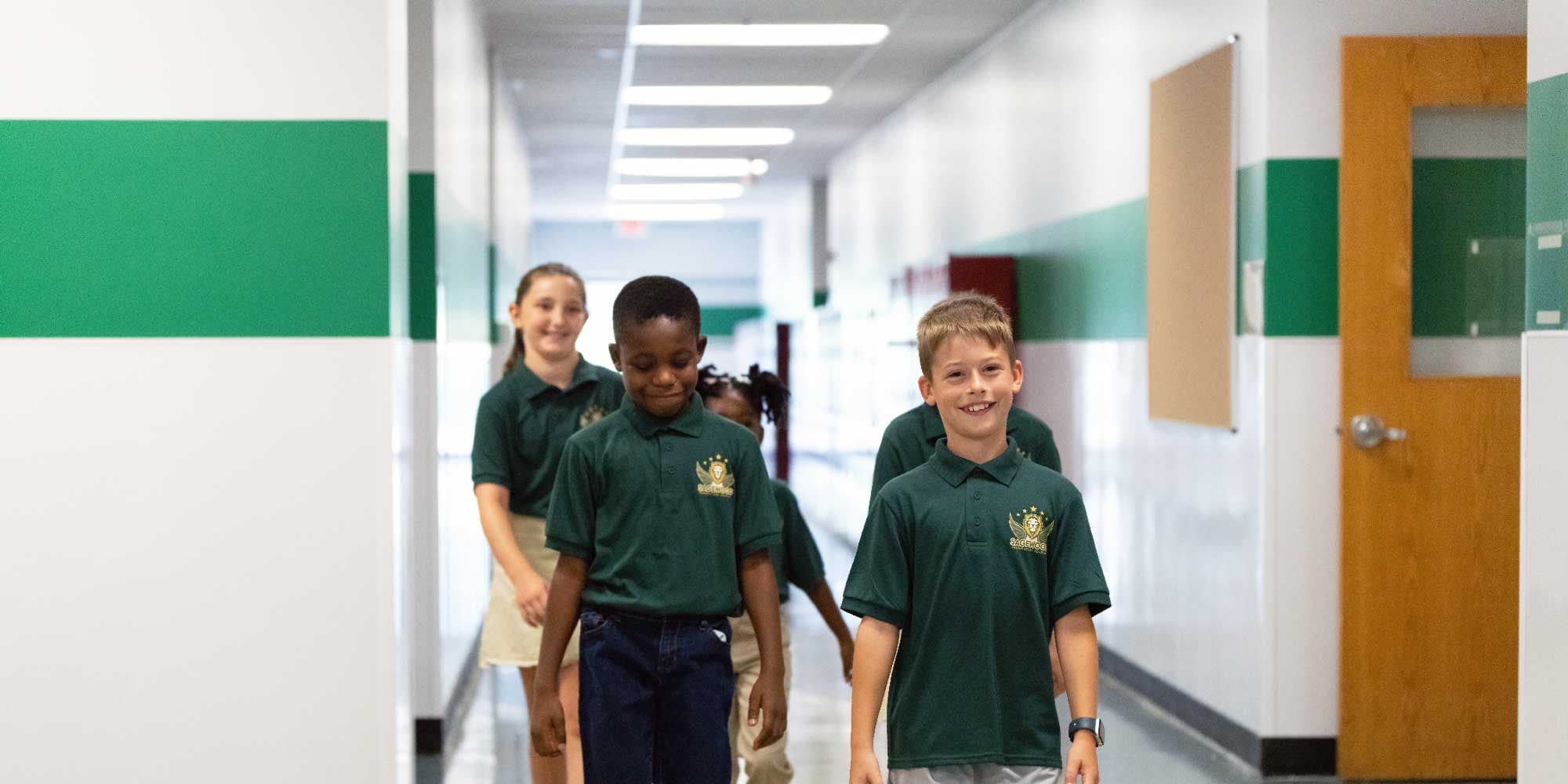 Students in green Sagewood polo shirts walking down a school hallway.